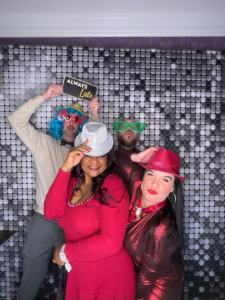 Invités avec des accessoires devant un photobooth de party de Noël