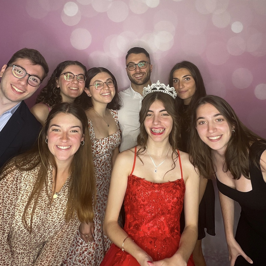 Quinceañera entourée de ses invités devant la toile rose du photobooth